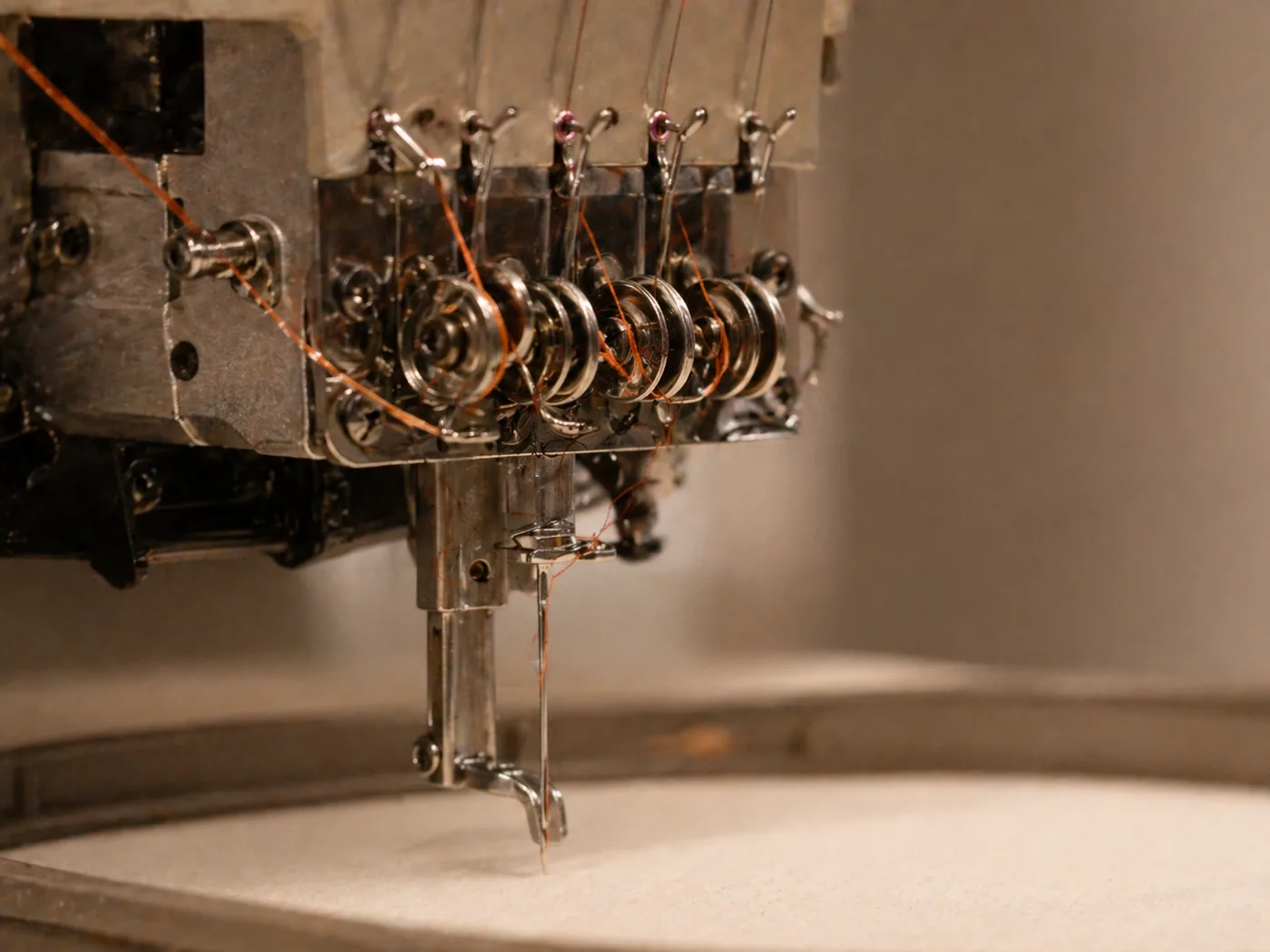 Крупный план вышивальной машины — терракотовая нить через механизм натяжения